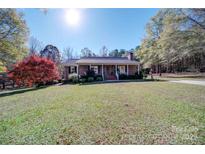 Charming brick ranch home with a lush front yard, inviting porch and beautiful mature trees at 857 Providence Rd, Lancaster, SC 29720