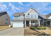 Charming two-story home with blue and gray siding, a two-car garage, and a cozy front porch at 913 Deep River Way, Waxhaw, NC 28173