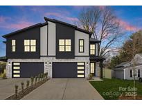 Modern home with a two-car garage, stone accents, and gray siding against a colorful evening sky at 2205 Catalina Ave, Charlotte, NC 28206