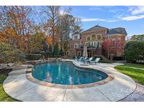 Backyard view featuring a beautiful in-ground pool, lounge chairs, and mature trees surrounding the property at 18912 Peninsula Point Dr, Cornelius, NC 28031
