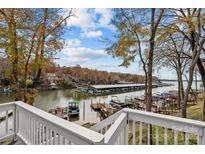 Scenic lake view from a waterfront property with boat docks and autumn foliage, seen from white porch railing at 26022 Misty Way Dr, Tega Cay, SC 29708