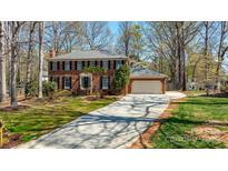 Traditional two-story brick home with a well-manicured lawn and a long driveway leading to an attached garage at 2605 Willowdale Ln, Matthews, NC 28105