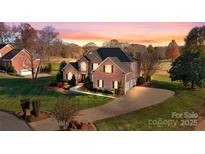 Stately brick home boasts mature landscaping, long driveway, and three-car garage at 2425 Birdie Ne Ln, Conover, NC 28613