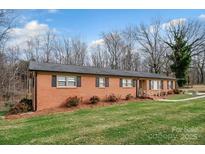 Charming red brick home with a well-maintained lawn and mature trees creating a serene curb appeal at 216 Delview Dr, Cherryville, NC 28021