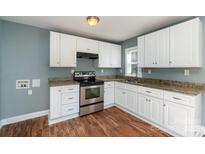 Bright kitchen features white cabinets, stainless steel appliances, granite counters, and wood flooring at 2630 Druid Hills Way, Charlotte, NC 28206