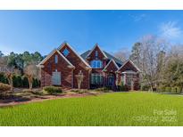 Stunning brick home with manicured lawn, intricate rooflines, and arched entry, offering classic elegance and curb appeal at 1038 Rolling Park Ln, Fort Mill, SC 29715