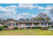 Brick ranch house with a covered porch, well-manicured lawn, and mature trees at 106 Fox Run Dr, Fort Mill, SC 29715