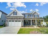 Two-story home with stone accents and a three-car garage at 3252 Mcharney Dr # 37, Harrisburg, NC 28075