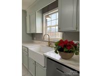 Renovated kitchen with white farmhouse sink, quartz countertops, and light green cabinets at 129 Mapleleaf Rd, Statesville, NC 28625