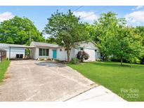 Charming home featuring a vibrant turquoise door, mature trees, and lush green lawn at 549 Spring Sw St, Concord, NC 28025