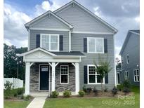 Two-story home with gray siding, black shutters, stone accents, and a covered front porch at 9601 Pointer Rd # 77, Huntersville, NC 28078