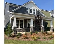 Charming home featuring gray siding, stone accents, a welcoming front porch, and professionally landscaped yard at 9605 Pointer Rd # 78, Huntersville, NC 28078