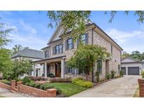 Brick two-story house with dark shutters, a front porch, and a driveway at 1117 Churchill Commons Dr, Charlotte, NC 28211