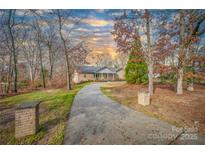 Charming single-story brick home with a long driveway and well-manicured lawn under a partially cloudy sky at 1115 Stony Point Rd, Kings Mountain, NC 28086