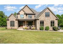 Charming stone-and-wood home featuring a covered front porch and well-manicured lawn at 174 Bellingshire Dr, Mt Ulla, NC 28125