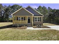 Charming single-story home with wood siding, covered porch, and manicured front yard at 625 Charles St, Rockwell, NC 28138