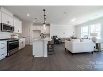 Open-concept living room with a modern kitchen, hardwood floors, and bright, natural light from the surrounding windows at 5680 Clear Creek Ln, Charlotte, NC 28215