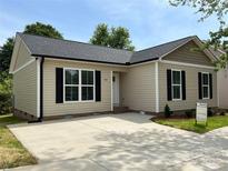 Charming single-story home with vinyl siding, black shutters, and a concrete driveway on a sunny day at 702 Park Ave, Salisbury, NC 28144