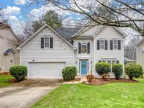 Charming two-story home features white siding, attached garage and inviting blue front door with beautiful landscaping at 17628 Cambridge Grove Dr, Huntersville, NC 28078