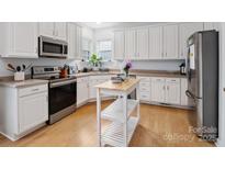 Bright kitchen with stainless steel appliances, white cabinets, light countertops and a movable kitchen island at 17628 Cambridge Grove Dr, Huntersville, NC 28078