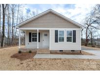 Newly constructed home with light beige vinyl siding, a covered porch, and a brick walkway at 25 Kesler St, Salisbury, NC 28144