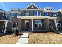 Charming brick townhome featuring gray shutters, a covered porch, and well-manicured landscaping at 5544 Stafford Rd # 30, Charlotte, NC 28215