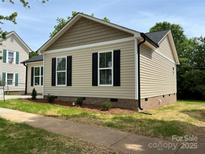 A charming home with beige siding, black shutters, and manicured landscaping, nestled on a sunny corner lot at 718 Park Ave, Salisbury, NC 28144