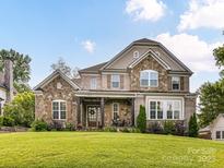 Charming stone and brick home featuring a manicured front lawn and inviting covered porch at 3227 Pinehurst Pl, Charlotte, NC 28209