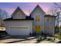 Charming home boasting a two-car garage and a vibrant yellow front door under a twilight sky at 10221 Hanging Moss Trl, Mint Hill, NC 28227