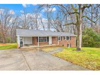 Brick ranch house with carport and mature trees in the front yard at 7006 Penndale Dr, Shelby, NC 28152