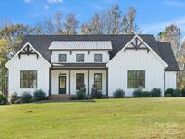 Charming white farmhouse with black trim, covered porch, and well-manicured lawn on a sunny day at 111 Alberta Ave, Belmont, NC 28012