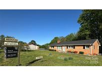 Charming single-story brick home featuring a well-manicured lawn and mature trees at 2319 Tin Mine Rd, Lincolnton, NC 28092