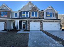 Two-story townhome with stone and siding exterior, two-car garage, and front yard at 4125 Black Ct # 169, Harrisburg, NC 28075
