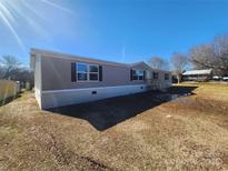 Single-wide mobile home with brown siding, steps and a spacious yard at 967 Perla Rd, York, SC 29745