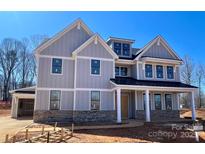 New construction gray two-story home featuring black trim windows and a welcoming front porch under a clear blue sky at 2007 Kendall Dr # 6, Wesley Chapel, NC 28173