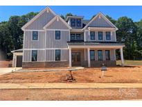 New two-story home with vertical siding, a metal roof, brick accents, and double front doors at 2007 Kendall Dr # 6, Wesley Chapel, NC 28173