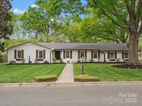Charming home featuring a manicured lawn, flower boxes, and a painted brick exterior at 1102 Oak Hill Dr, Monroe, NC 28112