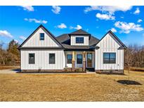 Stunning farmhouse exterior boasts white siding, a dark roof, and a charming front porch at 1215 Coppergate Dr, Salisbury, NC 28147