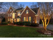 Elegant brick home featuring lush landscaping, arched windows, and warm exterior lighting at 13101 Whisper Creek Dr, Charlotte, NC 28277
