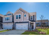 Charming two-story home featuring a light color palette, two-car garage, and manicured lawn under a clear blue sky at 165 Halite Ln, Waxhaw, NC 28173