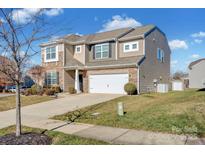 Two-story house with stone and siding accents, two-car garage, and landscaped lawn at 10436 Paisley Abbey Ln, Charlotte, NC 28273