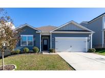 Charming single-story home features a two-car garage, manicured lawn, and blue siding under a clear blue sky at 138 Gray Willow St, Mooresville, NC 28117