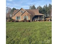 Brick ranch house with large yard, covered porch, and mature landscaping at 158 White Rd, Wadesboro, NC 28170