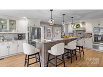 Spacious kitchen with granite island, stainless steel appliances, and white cabinetry at 8478 Rocky River Rd, Harrisburg, NC 28075