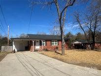 Charming brick home with a well-maintained front yard and covered parking on a sunny day at 1907 Steele St, Monroe, NC 28110