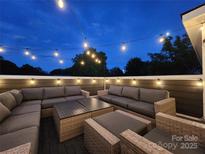 Inviting rooftop lounge area is illuminated by string lights for evening relaxation at 327 Coxe Ave, Charlotte, NC 28208