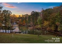 Scenic sunset view of lake with wooded shoreline and private dock at 51 Old Post Rd, Lake Wylie, SC 29710