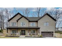Charming brick home featuring a covered front porch with stone accents and a two-car garage at 1312 Pleasant Plains Rd, Matthews, NC 28105