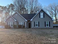 Gray house with black shutters, a black roof, and a well-maintained lawn at 13410 Old Camden Rd, Midland, NC 28107