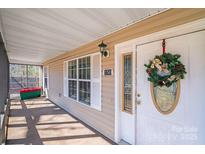 Covered front porch with white door, wreath, and ample light, offering a cozy and inviting entrance to the home at 150 Windmill Ct, Harmony, NC 28634